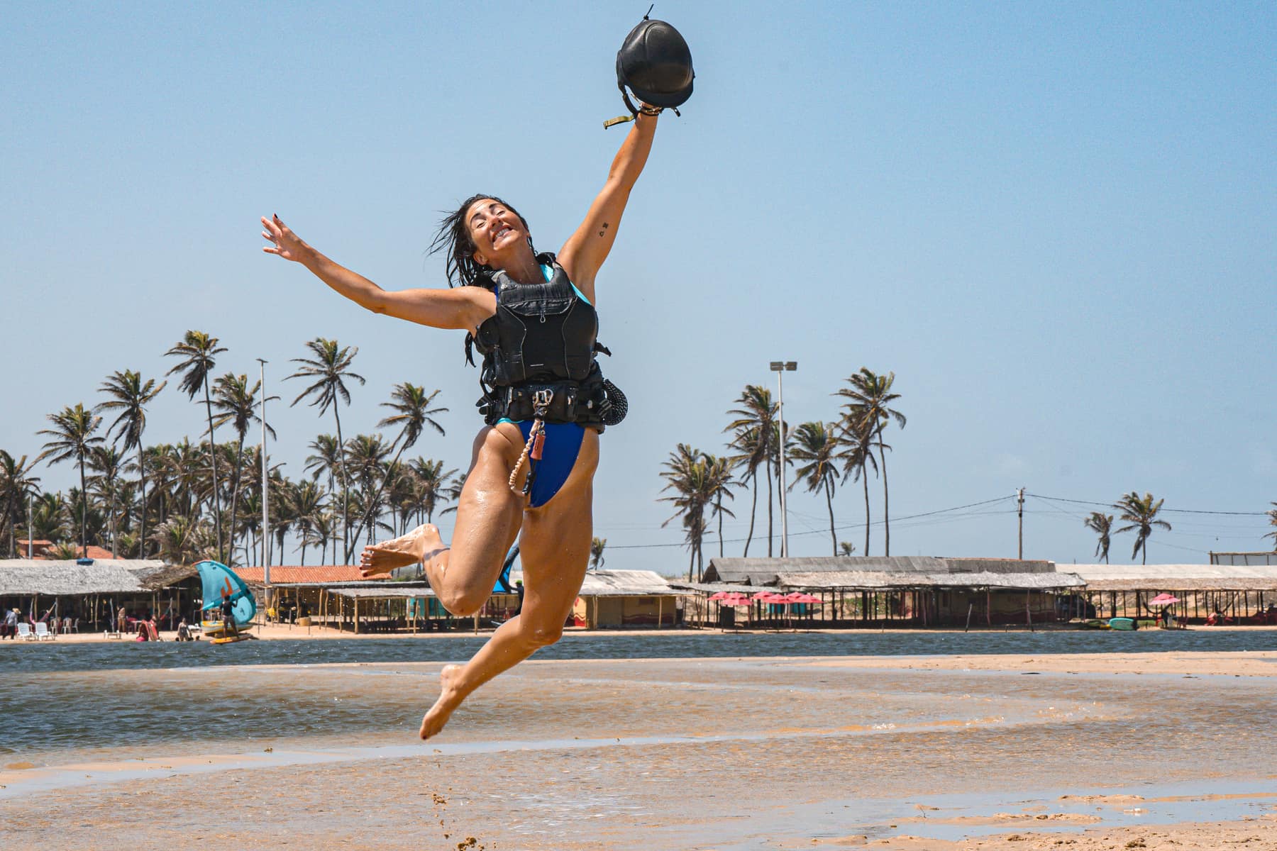 Woman jumping on a tropical Brazil kite spot with palm trees