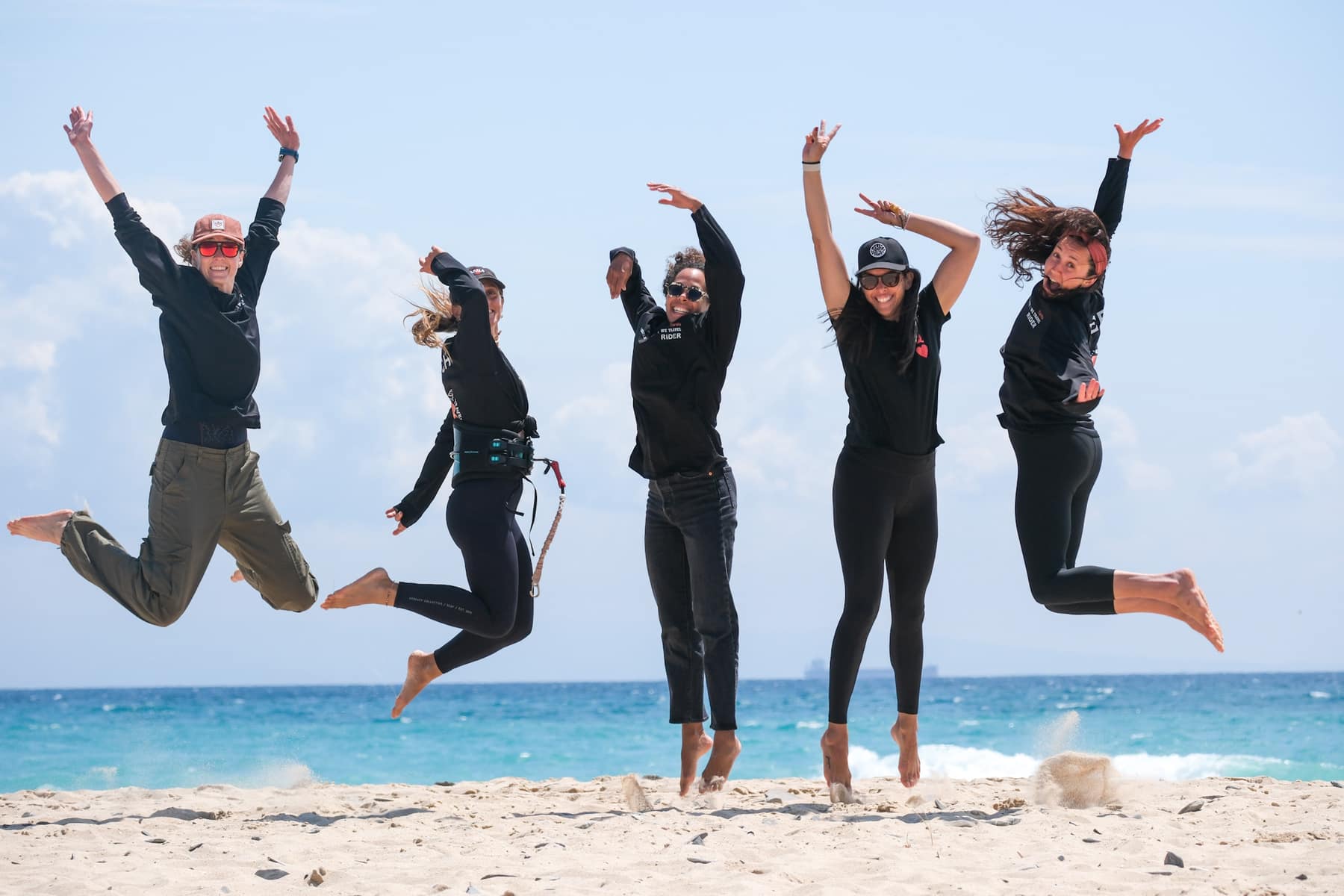 Women jumping together on Tarifa beach by the ocean