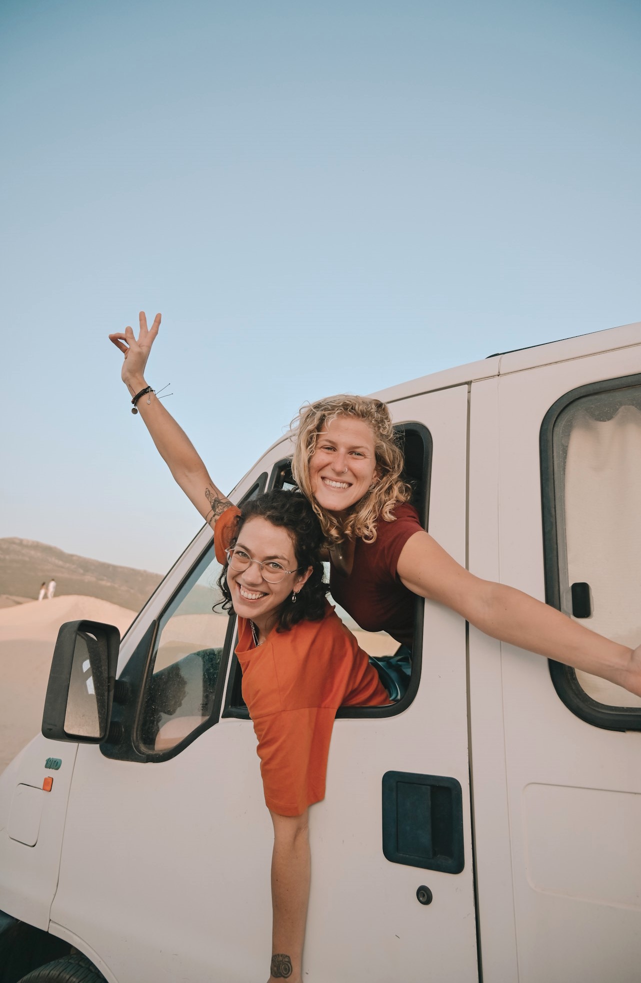Two women smiling from a van during a road trip